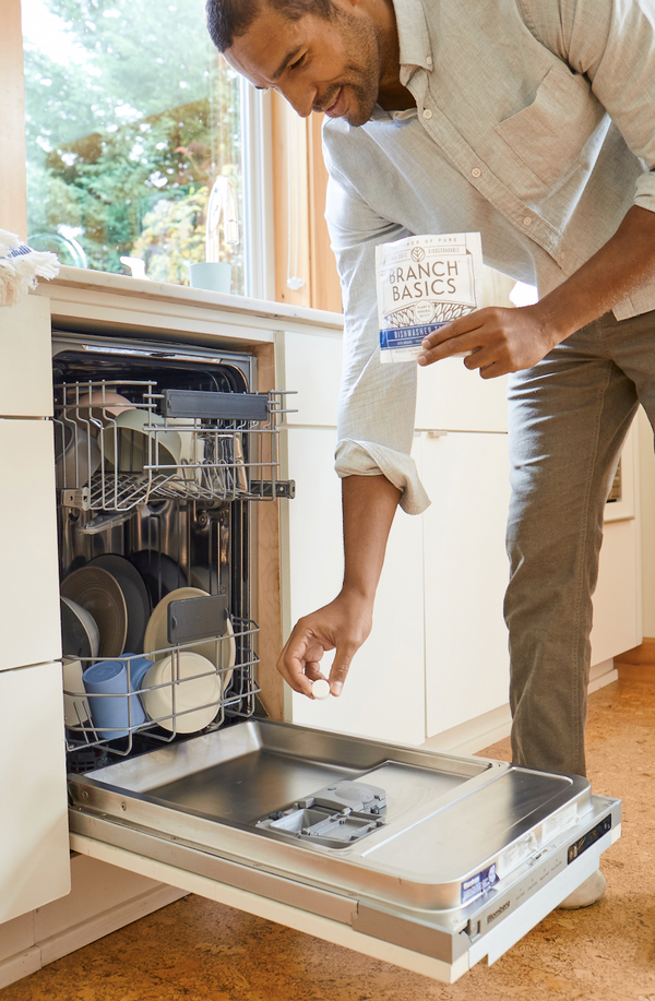 Man using Branch Basics Dishwasher Tablets to wash dishes in the dishwasher