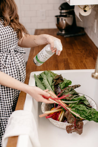 Woman spraying Branch Basics All-Purpose to naturally clean fruits and vegetables