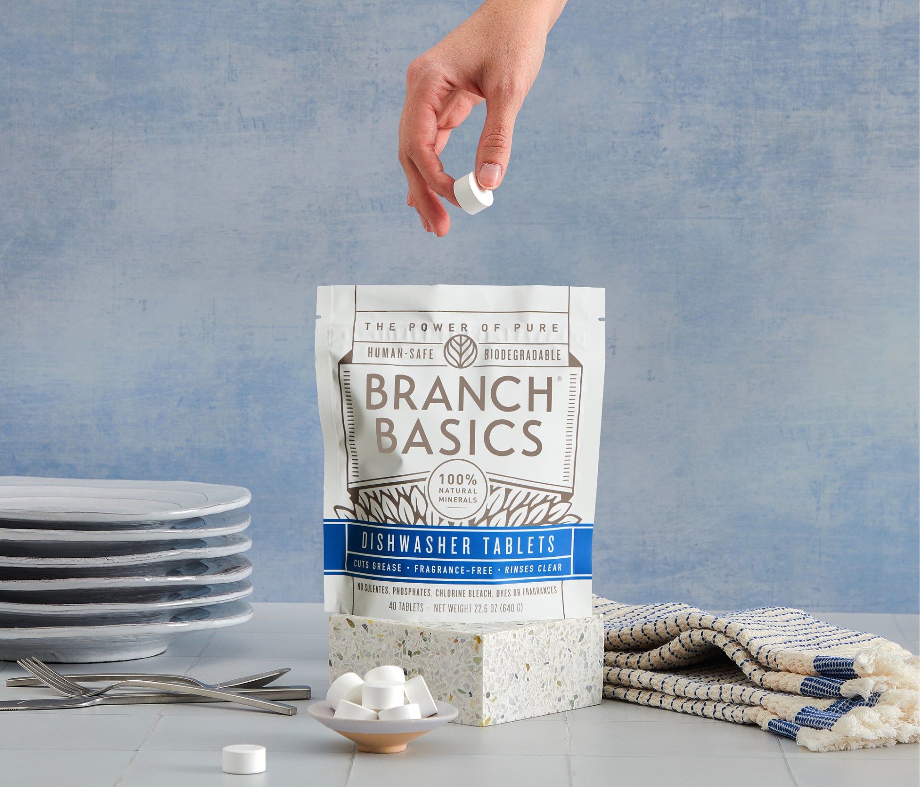 A standing bag of Dishwasher Tablets with a hand extracting a single Dishwasher Tablet from the bag. - View 2
