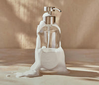 A single Glass Foaming Bottle with a Chrome pump covered in foaming bubbles against a neutral background. - Thumbnail View 9
