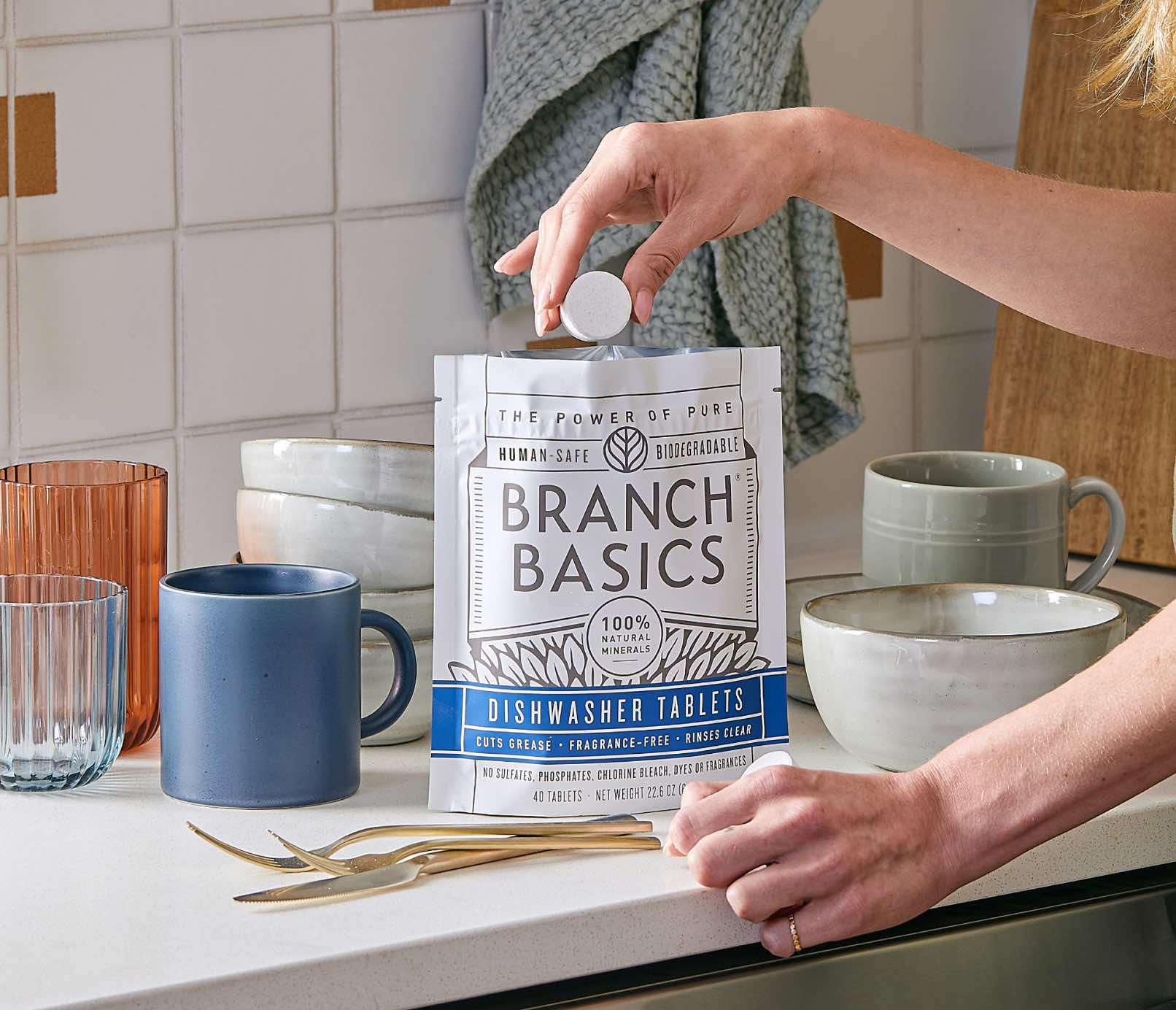 A standing bag of Dishwasher Tablets with a hand extracting a single Dishwasher Tablet from the bag. - View 7
