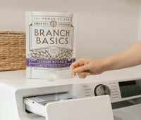A bag of Laundry Detergent on top of a washing machine, with a scoop of detergent being added to the washing machine. - Thumbnail View 8
