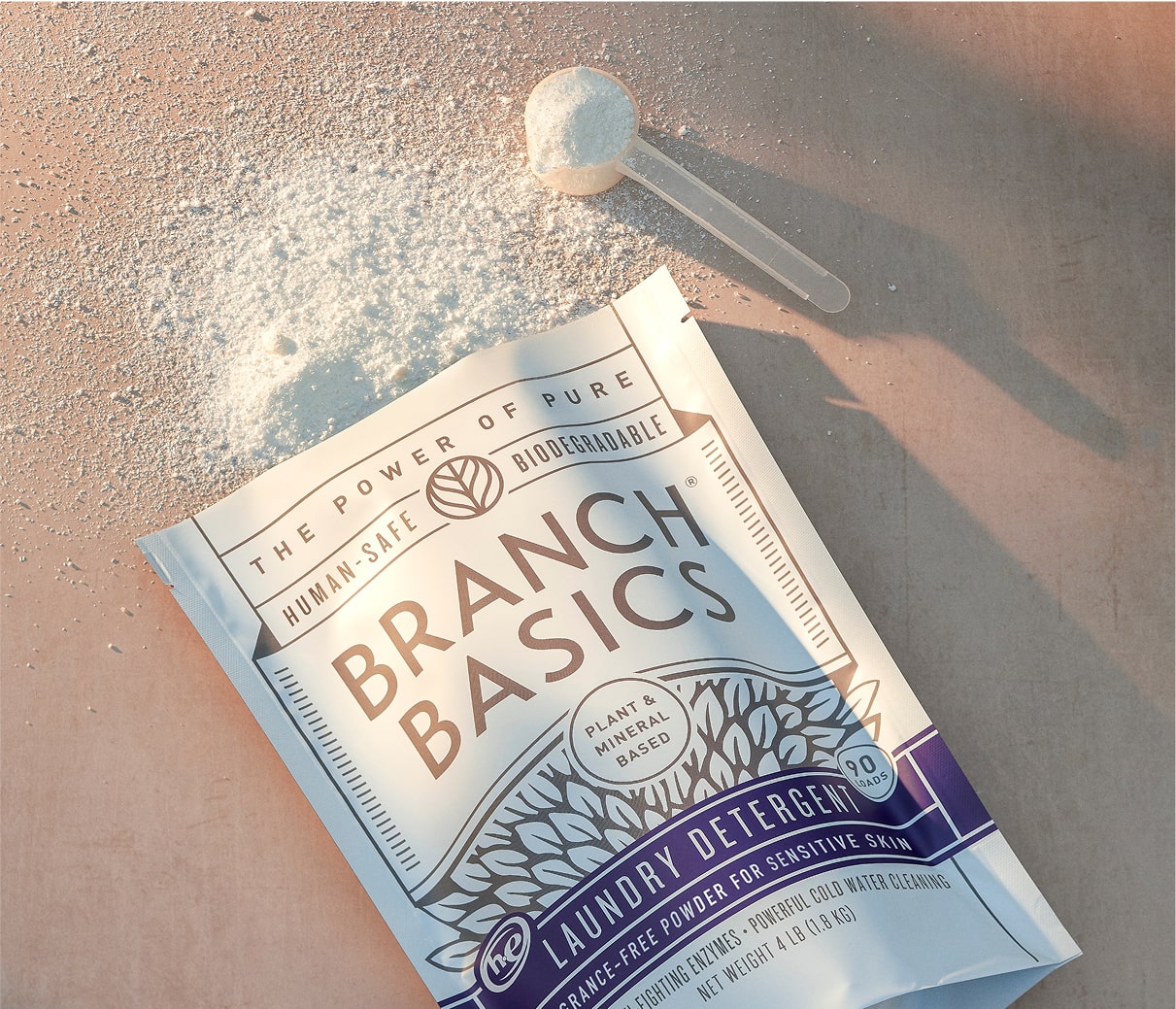 A pouch of Branch Basics Laundry Detergent laying open and on its side, spilling powder out of the top. - View 3
