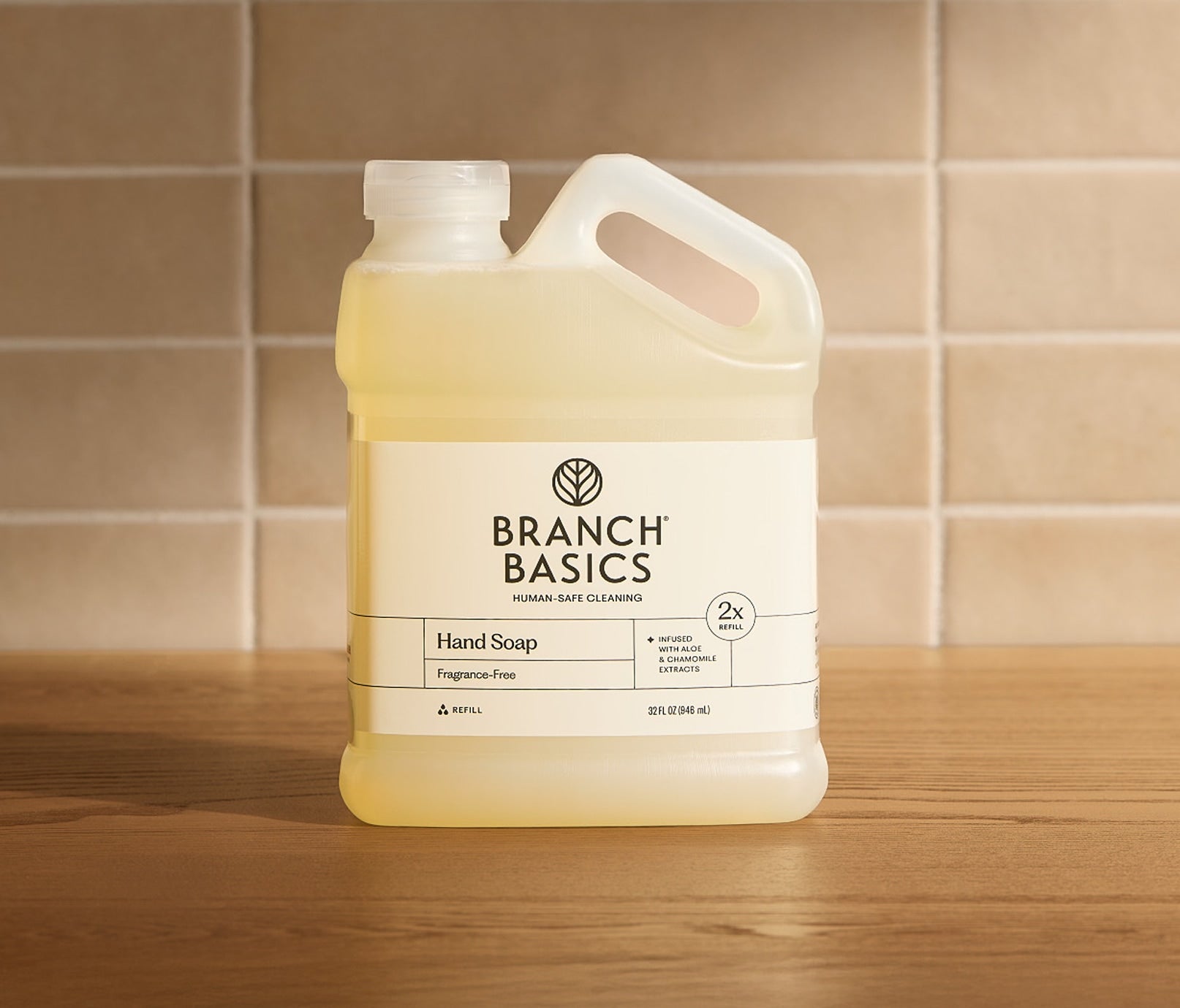 Branch Basics hand soap refill bottle on a wooden surface with a tiled wall background - View 1
