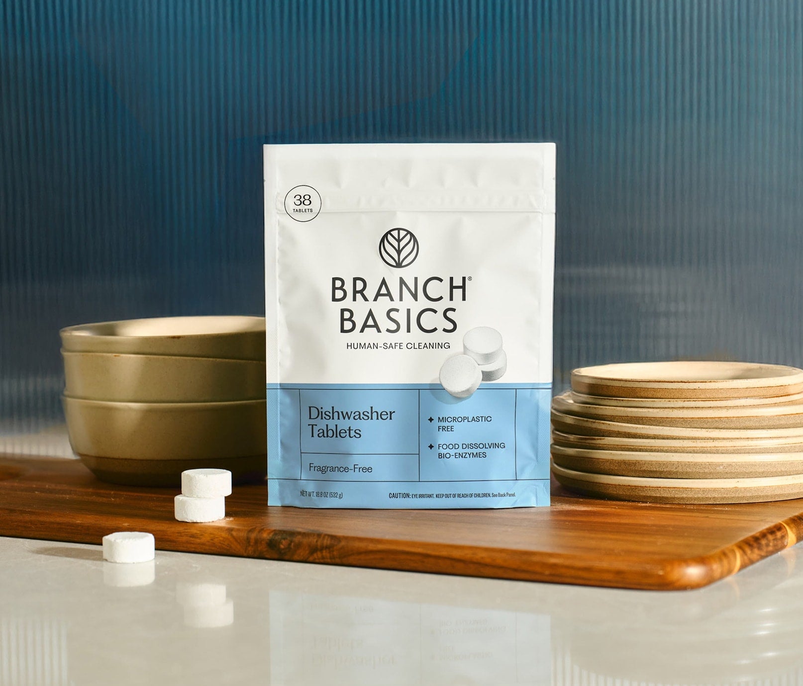 Branch Basics Dishwasher Tablets packaging on a wooden cutting board with bowls and plates in the background. - View 1

