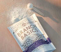 A pouch of Branch Basics Laundry Detergent laying open and on its side, spilling powder out of the top. - Thumbnail View 3
