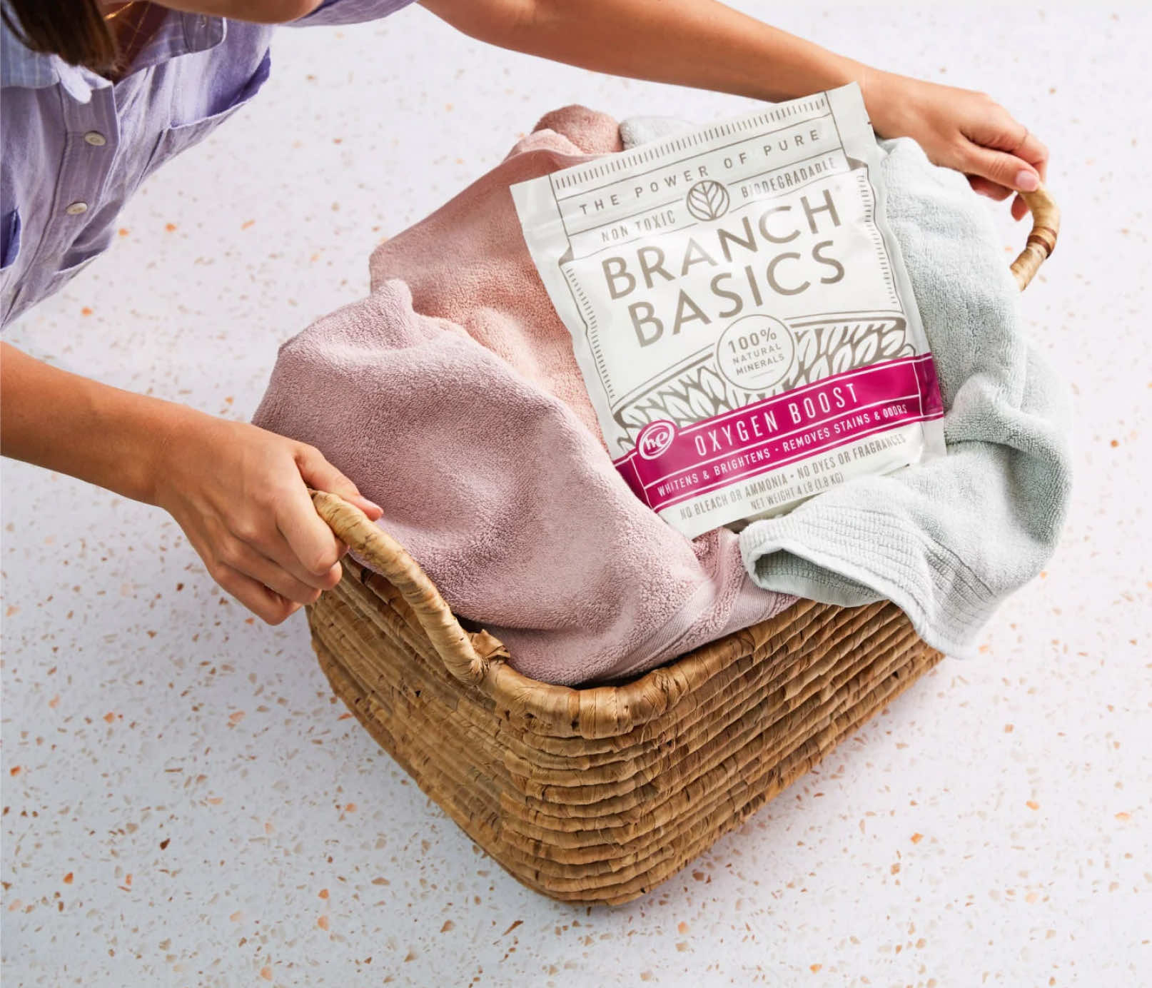 A full laundry basket with a pouch of Branch Basics Oxygen Boost sitting on top. - View 4
