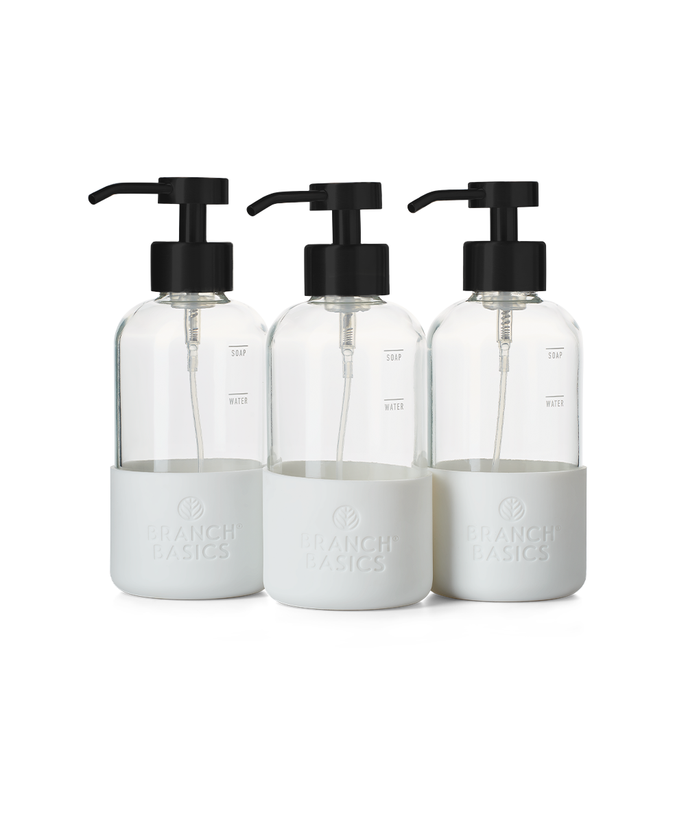 A trio of refillable Glass Foaming Wash Bottles with Matte-Black pumps, displayed on a transparent background. - View 1
