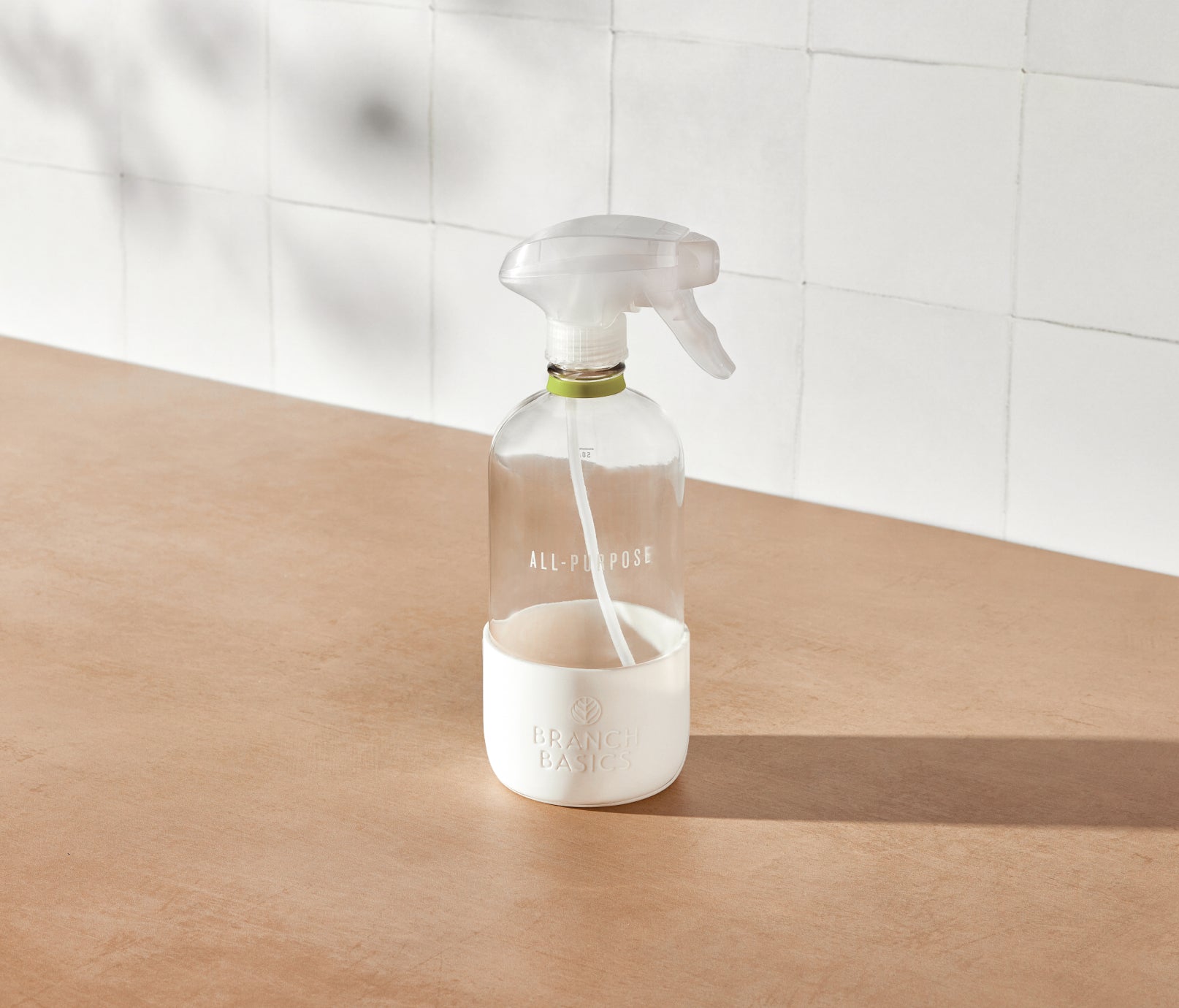 A refillable Glass All-Purpose bottle, used to dilute and dispense Branch Basics Concentrate with water, displayed on a neutral surface and white tiled background. - View 2
