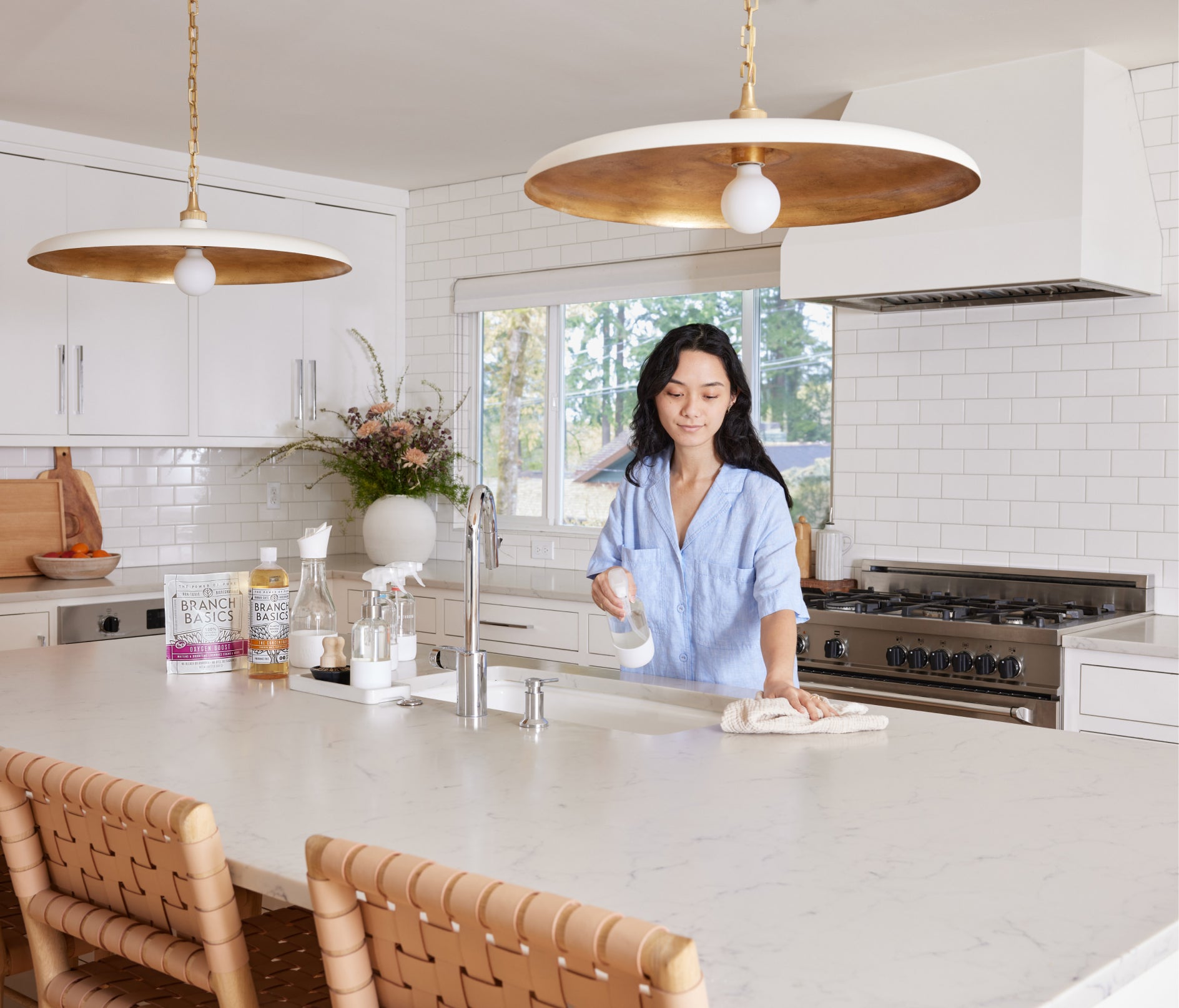 The Premium Starter Kit featuring Glass bottles displayed on a kitchen counter with a woman wiping the counter with a hand towel. - View 7
