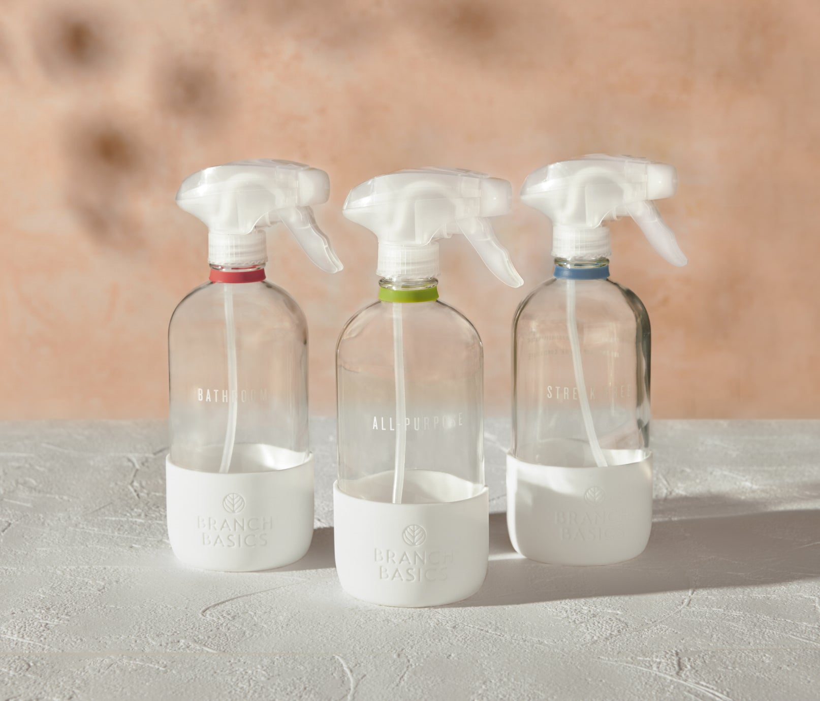 The Glass Bottles Essentials Pack, featuring Bathroom, All-Purpose, and Streak-Free versions of Branch Basics refillable Glass bottles, displayed on a white surface and neutral background. - View 2
