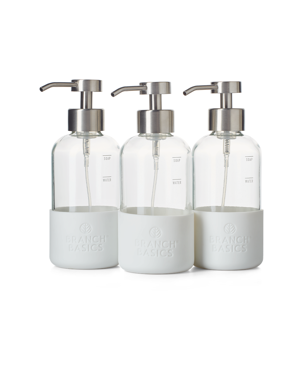 A trio of refillable Glass Foaming Wash Bottles with Brushed-Chrome pumps, displayed on a transparent background. - View 1
