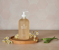 A glass bottle of Branch Basics Gel Hand soap, displayed on a wooden tray with a neutral tiled background. - Thumbnail View 3
