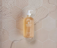 A glass bottle of Branch Basics Gel Hand soap, displayed on a neutral tiled background. - Thumbnail View 4
