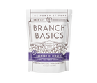 A pouch of Branch Basics Laundry Detergent powder. The packaging is white with purple and grey accents and text that highlights the product features, including 'plant-based formula' and 'human-safe, biodegradable'.