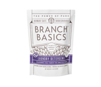 A pouch of Branch Basics Laundry Detergent powder. The packaging is white with purple and grey accents and text that highlights the product features, including 'plant-based formula' and 'human-safe, biodegradable'. - Thumbnail View 2
