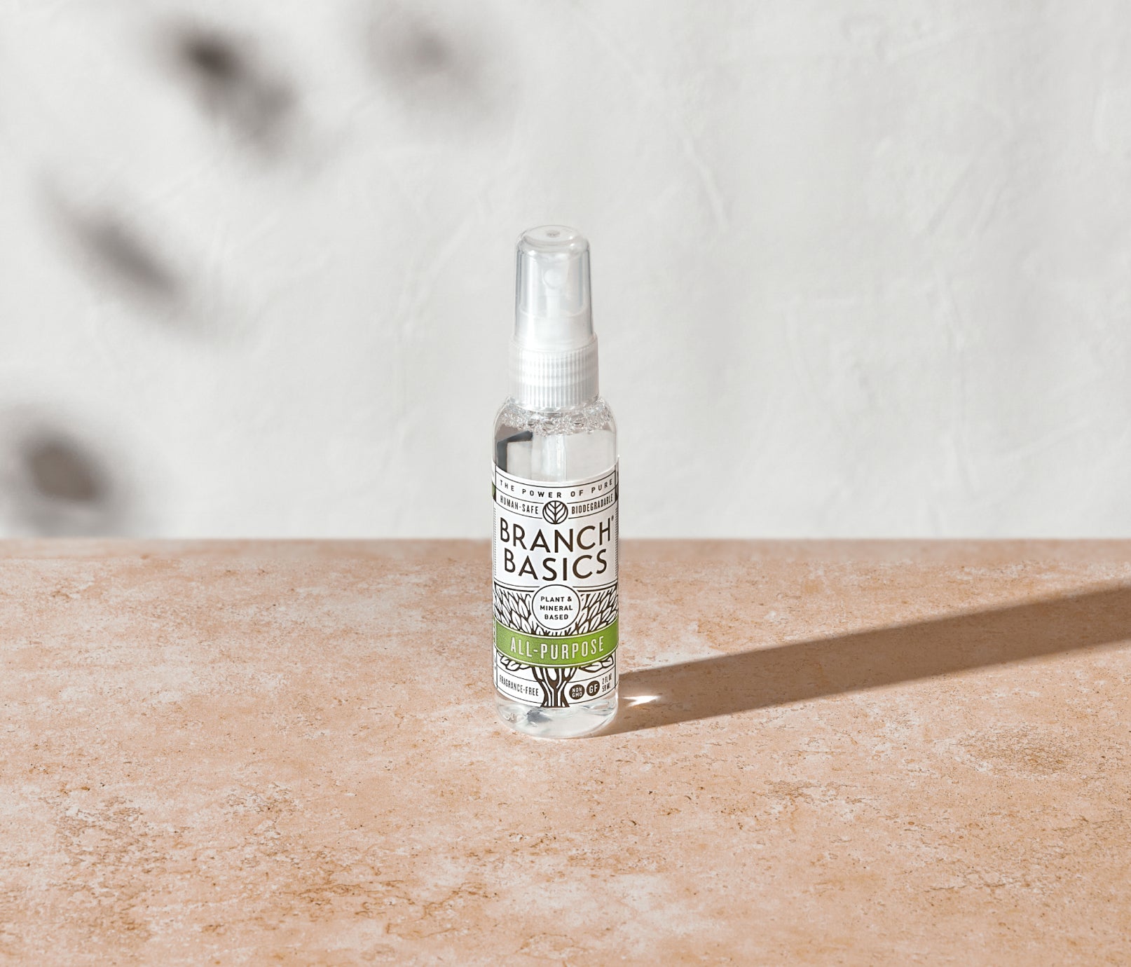 A mini-bottle of the Branch Basics All-Purpose spray, displayed on a neutral surface and white background. - View 2
