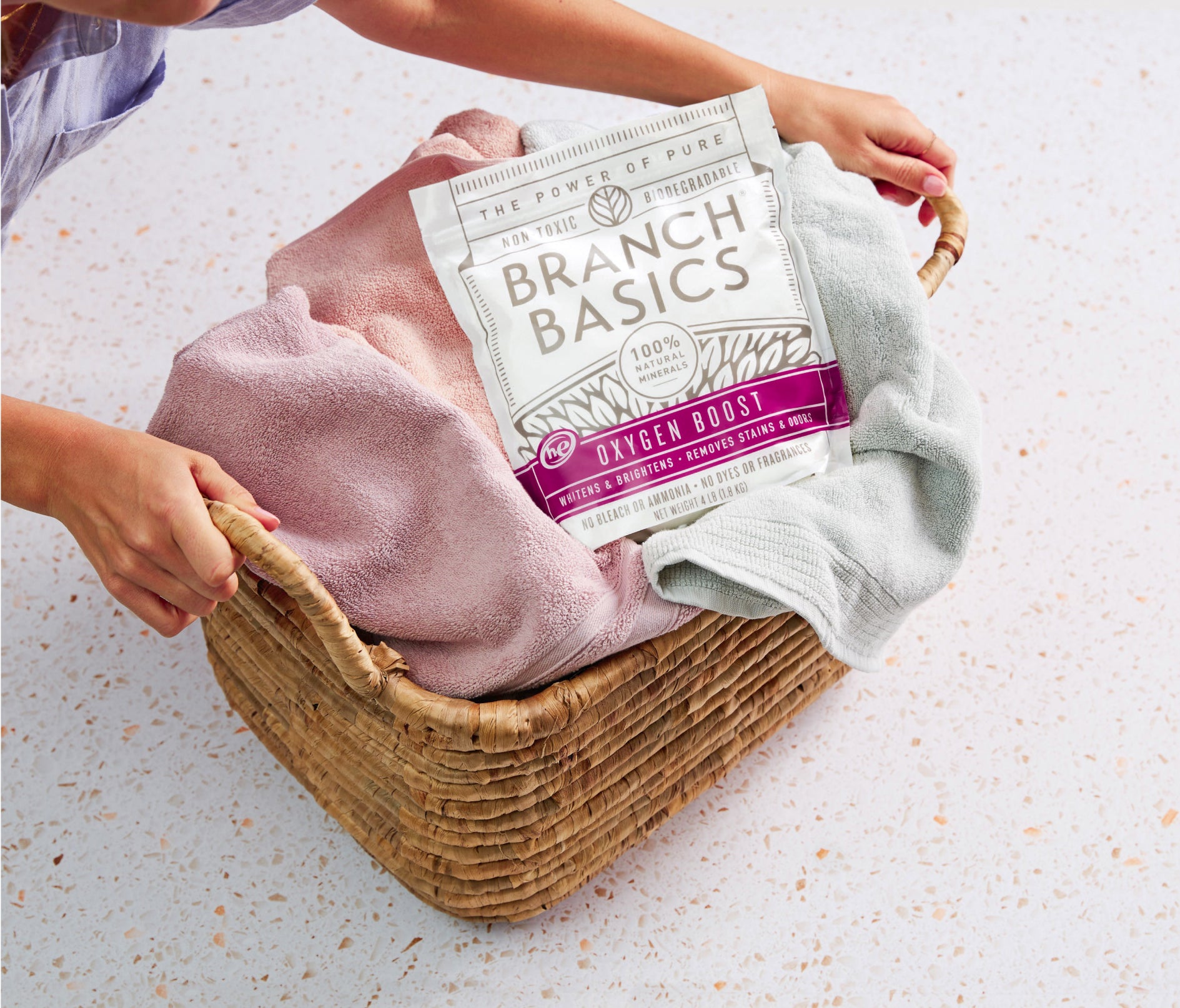 A full laundry basket with a pouch of Branch Basics Oxygen Boost sitting on top. - View 5
