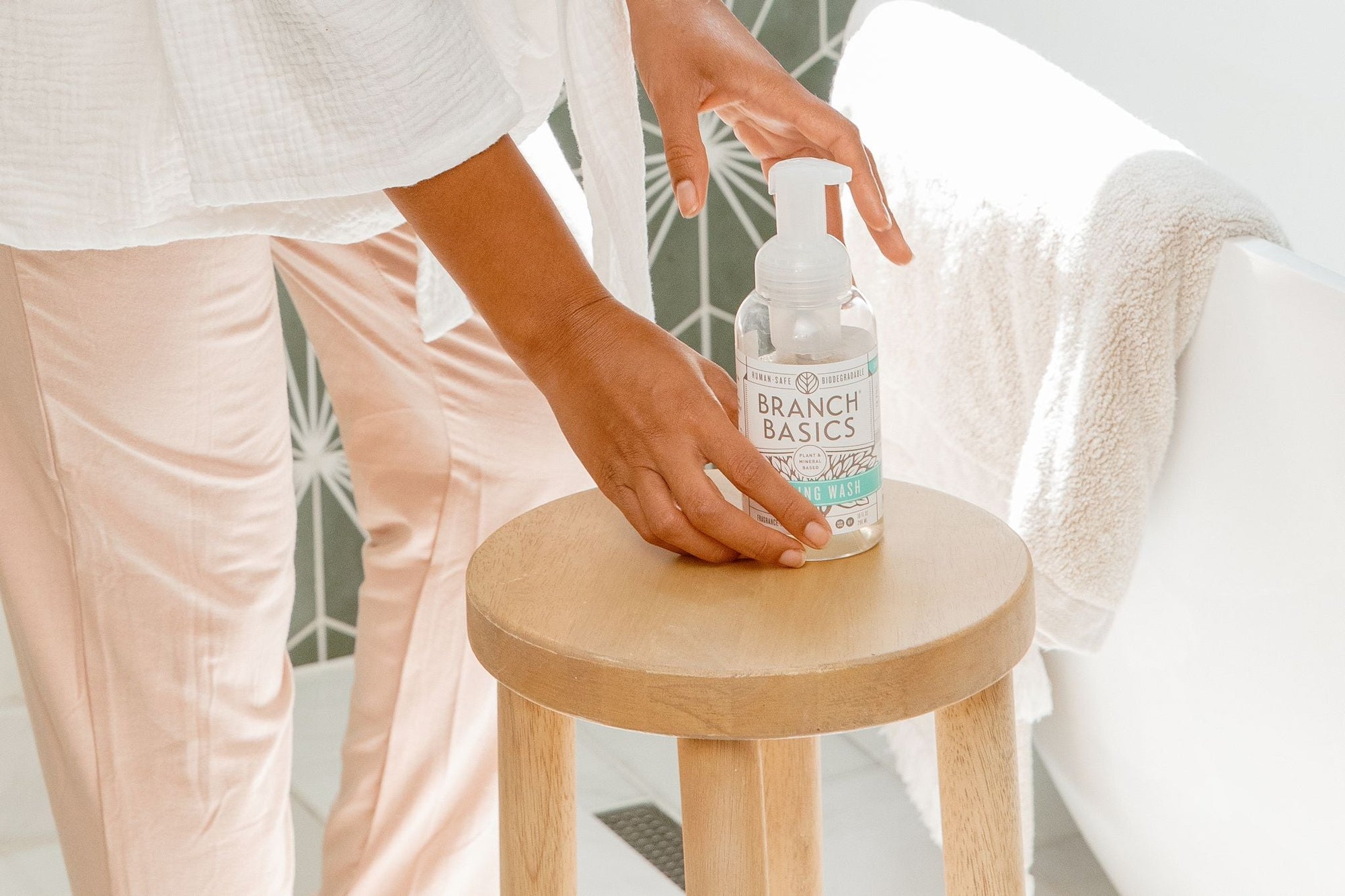 A single refillable Plastic Foaming Bottle placed on a wooden stool. - View 4
