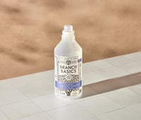 A refillable Plastic Laundry bottle, used to dilute and dispense Branch Basics Concentrate with water, displayed on a white tiled surface and neutral background. - Thumbnail View 2
