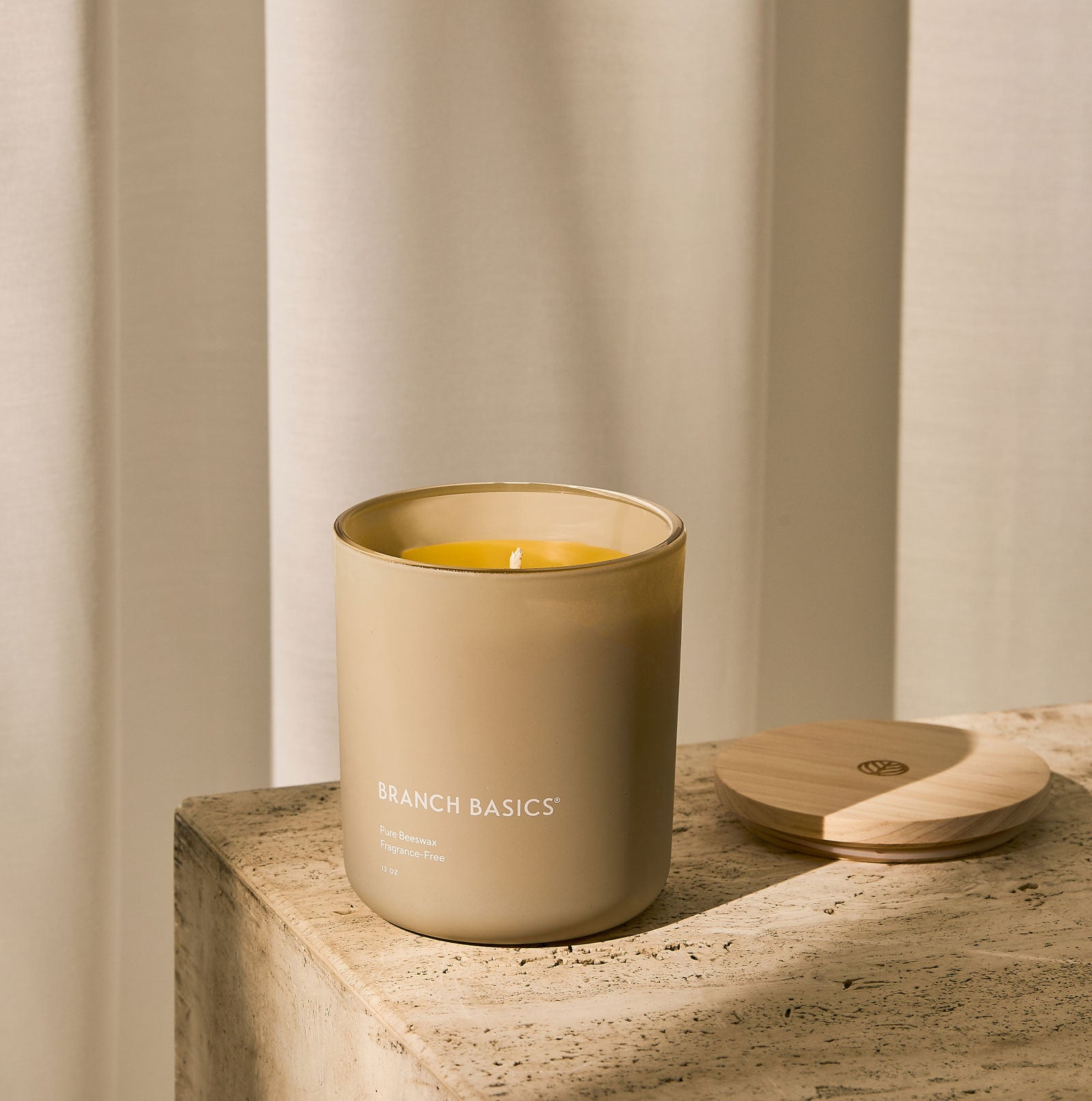 A Branch Basics 100% Beeswax Candle, housed in a glass jar with an organic cotton wick, displayed on a neutral background. - View 2
