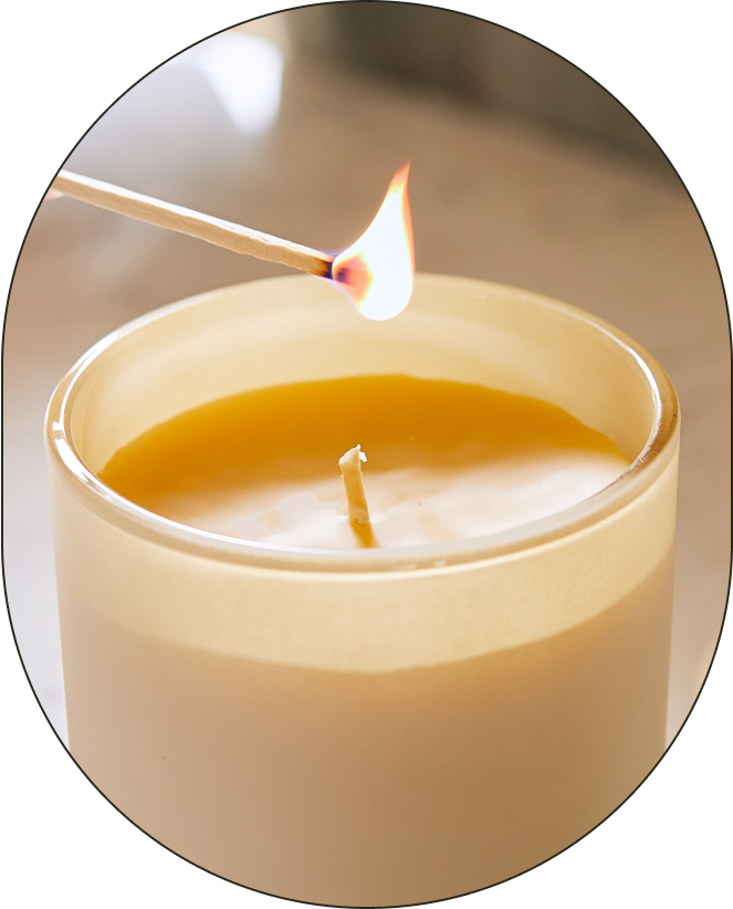 A lit match hovers over the organic cotton wick of a Branch Basics Beeswax Candle. - Card 2
