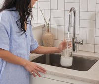 A person standing at a sink refilling a Glass Laundry bottle. - Thumbnail View 4
