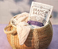 A pouch of Branch Basics Laundry Detergent tucked into a full laundry basket. - Thumbnail View 5
