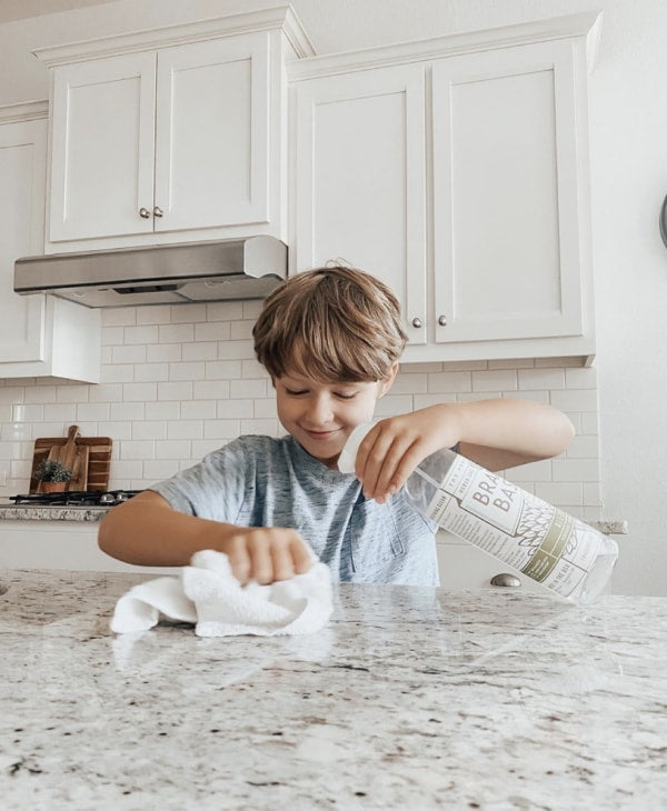 Boy cleaning with a Branch Basics spray bottle