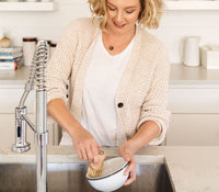 A person standing at a kitchen sink, using a Natural Scrub Brush to scrub dishes. - Thumbnail View 5
