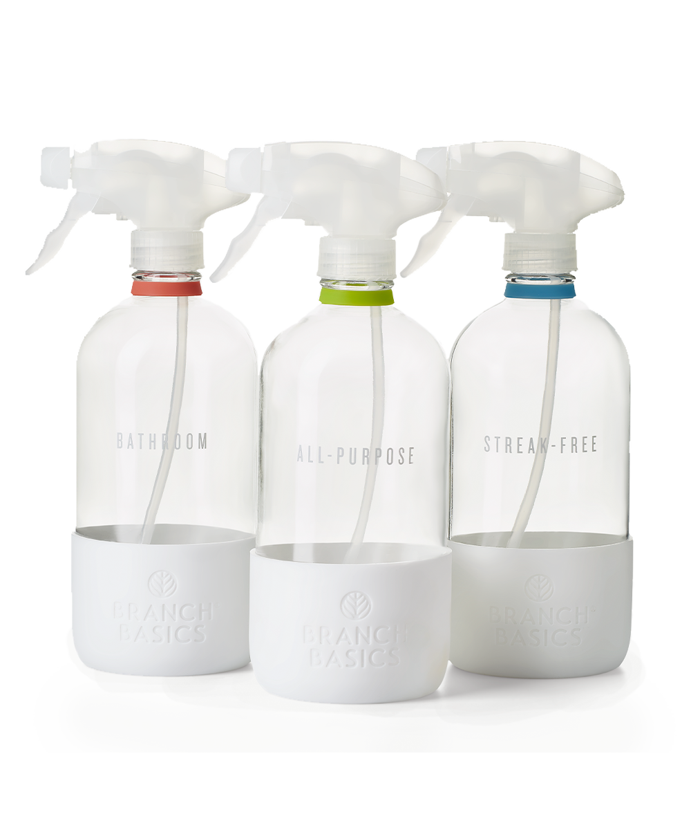 The Glass Bottles Essentials Pack, featuring Bathroom, All-Purpose, and Streak-Free versions of Branch Basics refillable Glass bottles, displayed on a transparent background. - View 1
