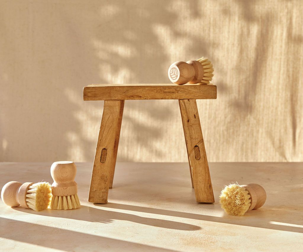Multiple Natural Scrub Brushes displayed on a neutral surface, with a single Brush elevated on a wooden stool. - View 4
